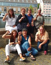 Foto: Weibernetz-Team, alle lachend an einer Mauer des Fuldaufers sitzend