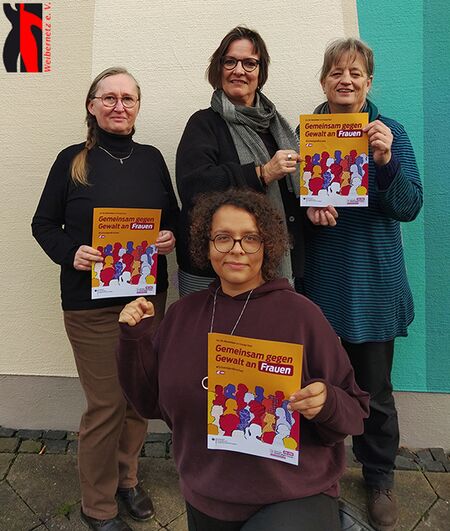 Die 4 Weibernetz-Kolleginnen halten Plakate vom Hilfetelefon Gewalt gegen Frauen mit der Aufschrift „Gemeinsam gegen Gewalt an Frauen“ hoch und blicken teils freundlich, teils resolut in die Kamera.