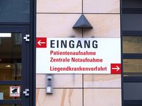 Schild an einer Hauswand mit der Aufschrift Eingang, Patientenaufnahme, Zentrale Notaufnahme, Liegendkrankenvorfahrt